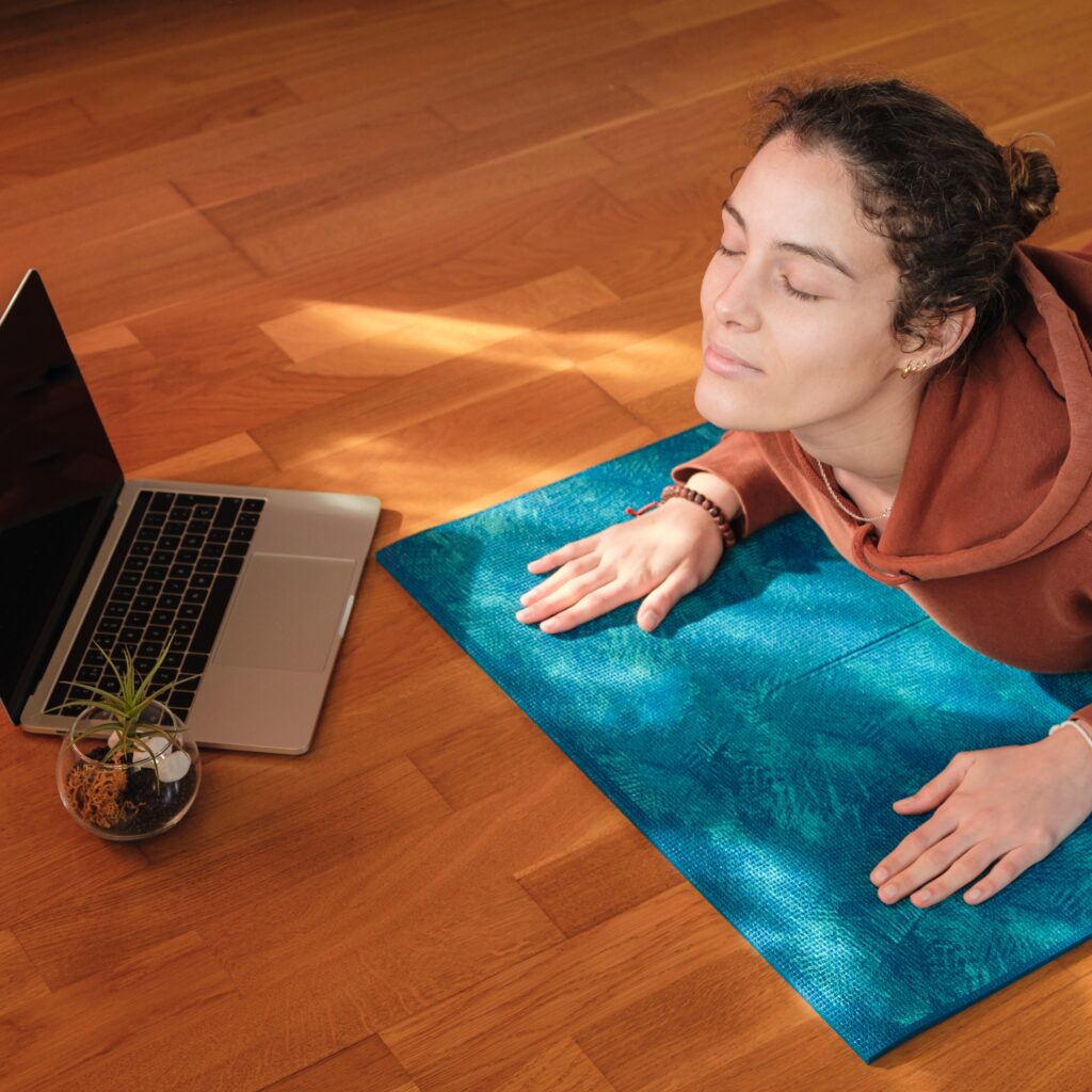 a female stretching over a mat during online yoga class